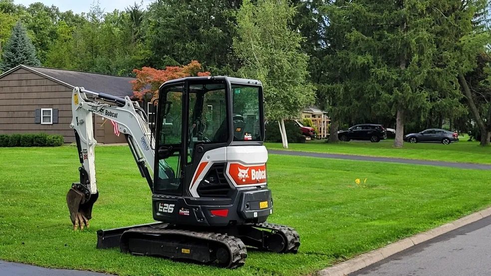 Bobcat mini excavator parked on a residential lawn on a Rochester NY property