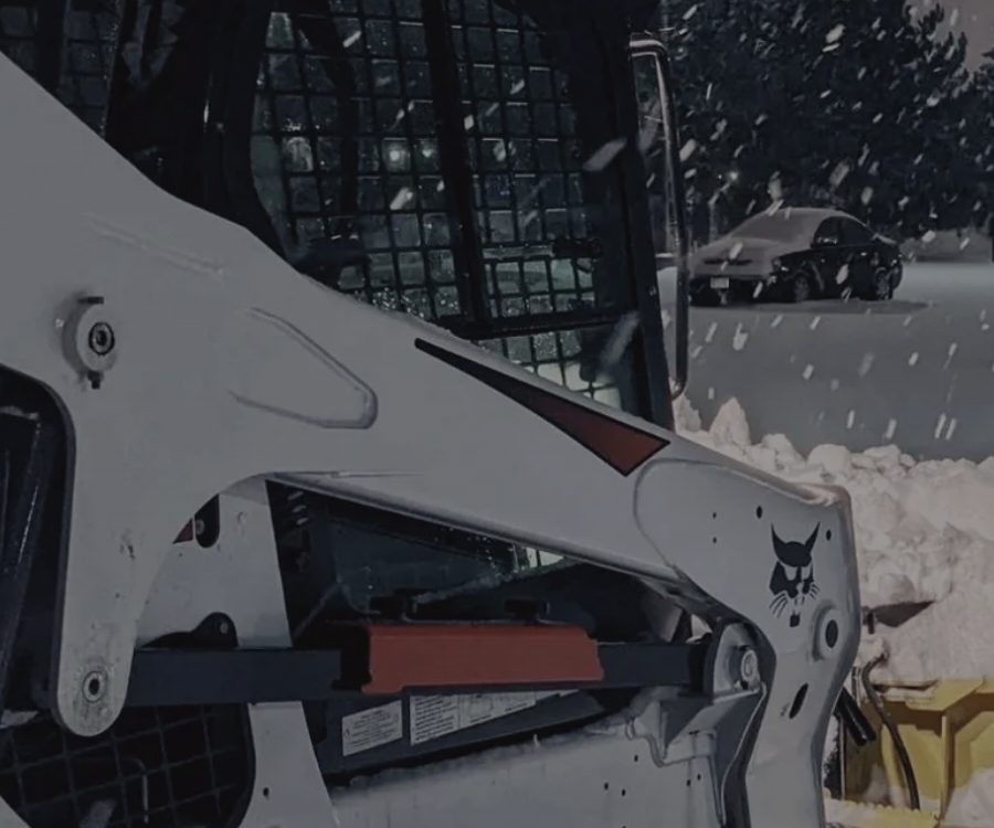 Track loader plowing snow at a commercial lot in Rochester NY