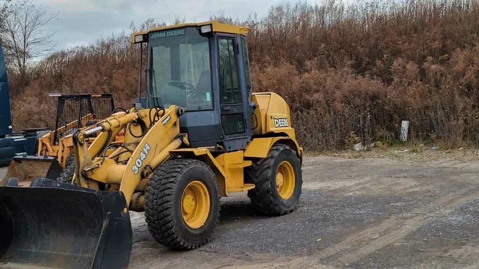 Yellow compact wheel loader with a bucket on a paved lot in Rochester NY