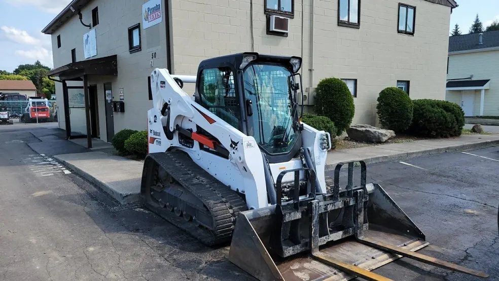 Bobcat compact track loader fitted with pallet forks outside an apartment complex in Rochester NY